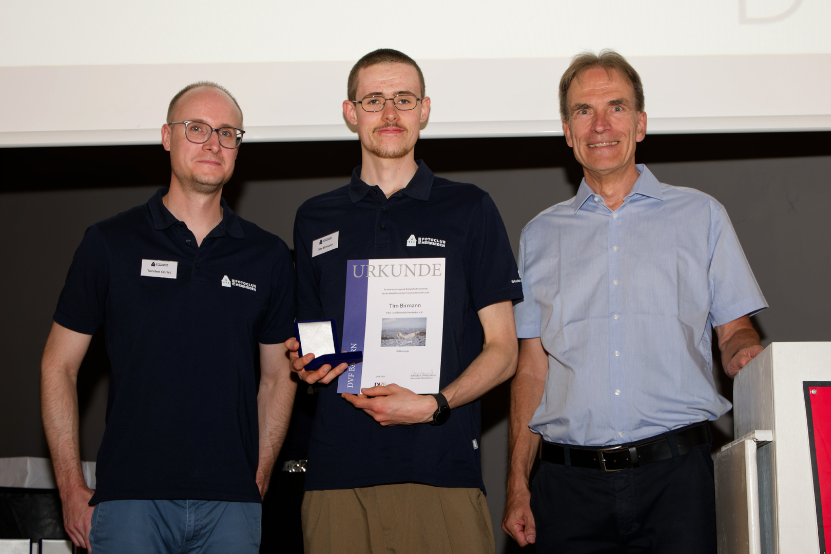 Medaille und Urkunde für Tim Birmann, verliehen von DVF-Bezirksleiter Ralf Hanisch (rechts); links Torsten Christ, Vorstand unseres Fotoclubs