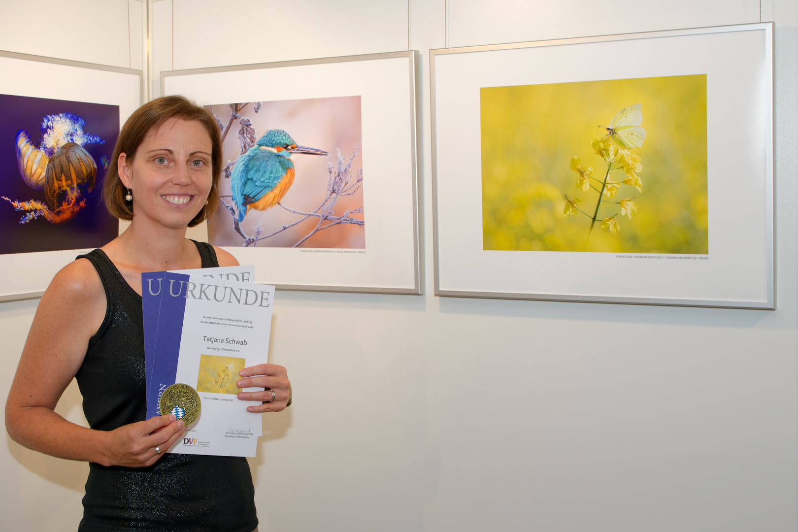 Tatjana Schwab vor ihren Bildern "Eisvogel im Morgenlicht" (ausgezeichnet mit Medaille) und "Zitronenfalter im Rapsfeld" (ausgezeichnet mit Urkunde)